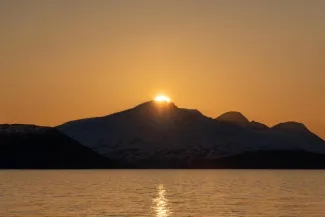 The midnight sun over the island of Reinøya in the Ullsfjord in Norway