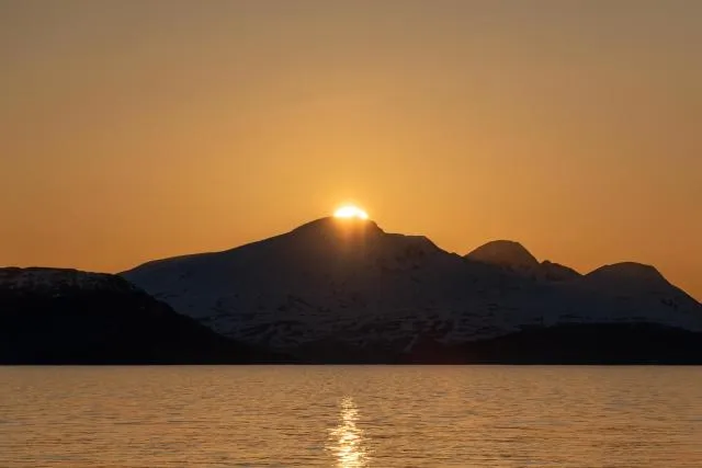 Die Mitternachtssonne über der Insel Reinøya im Ullsfjord in Norwegen