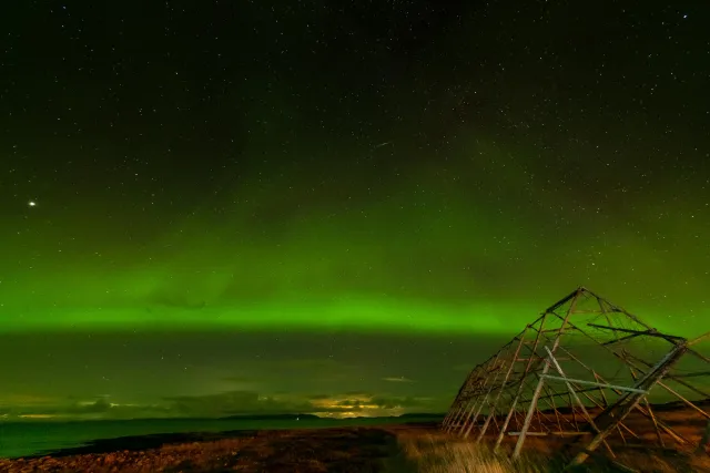 Northern lights over the fish drying racks in Ekkerøy with the rising moon